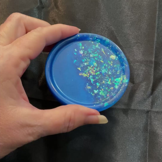 Video of the handmade small round ocean blue resin trinket dish showing how the blue glitter flakes sparkle in the light.