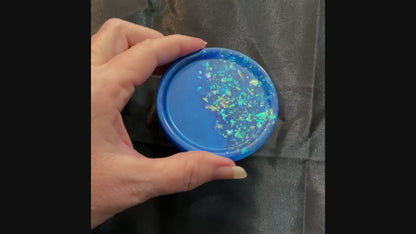 Video of the handmade small round ocean blue resin trinket dish showing how the blue glitter flakes sparkle in the light.