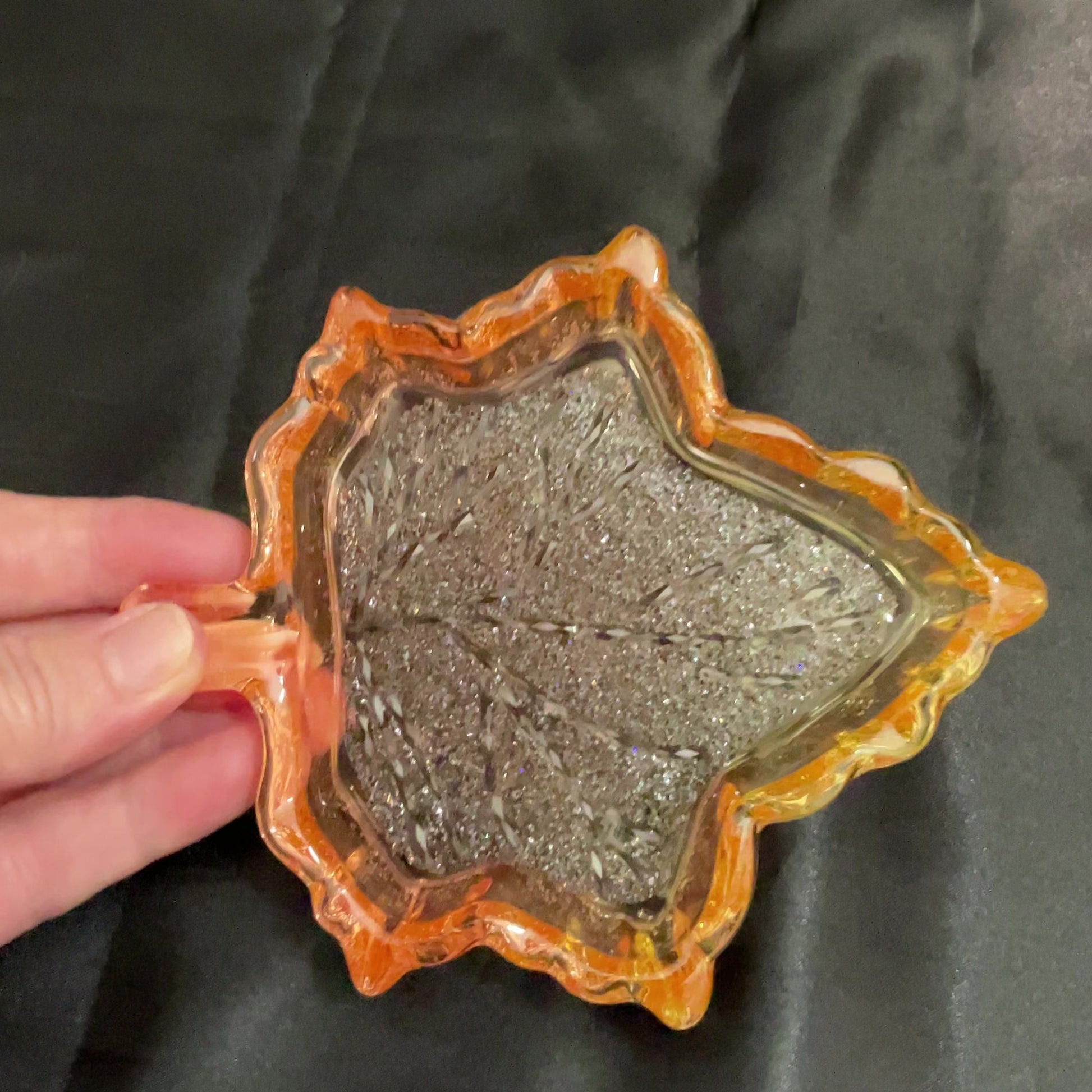 Video of the handmade translucent orange and yellow  resin leaf decorative trinket dish showing how the bottom faceted crystal like area sparkles in the light.