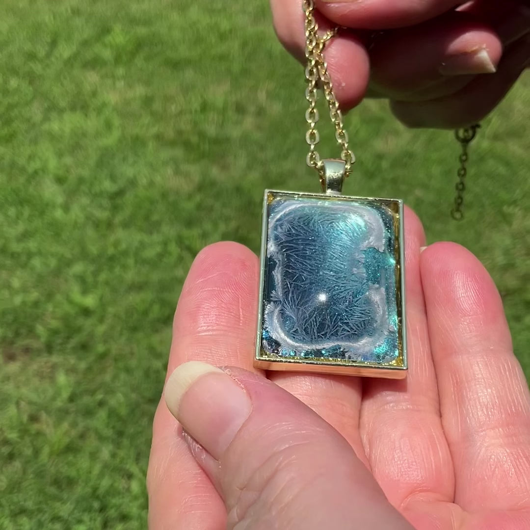 Handmade Abstract Blue Frost Resin Pendant Necklace video showing how the iridescent background shimmers and changes shade in the light.