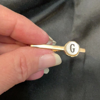 Video of the initial letter G tie clip clasp with mother of pearl shell showing how the shell cab has flashes of pearly white in the light.