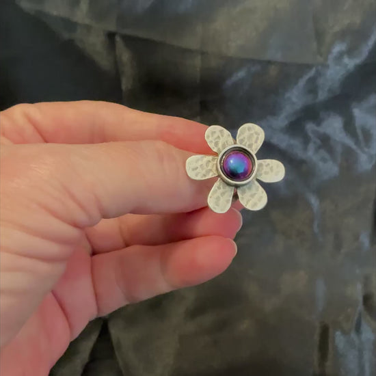 Video of the color shift flower ring showing how the resin cab shifts through shades of pink, blue, purple, yellow and green depending on how the light is hitting it.