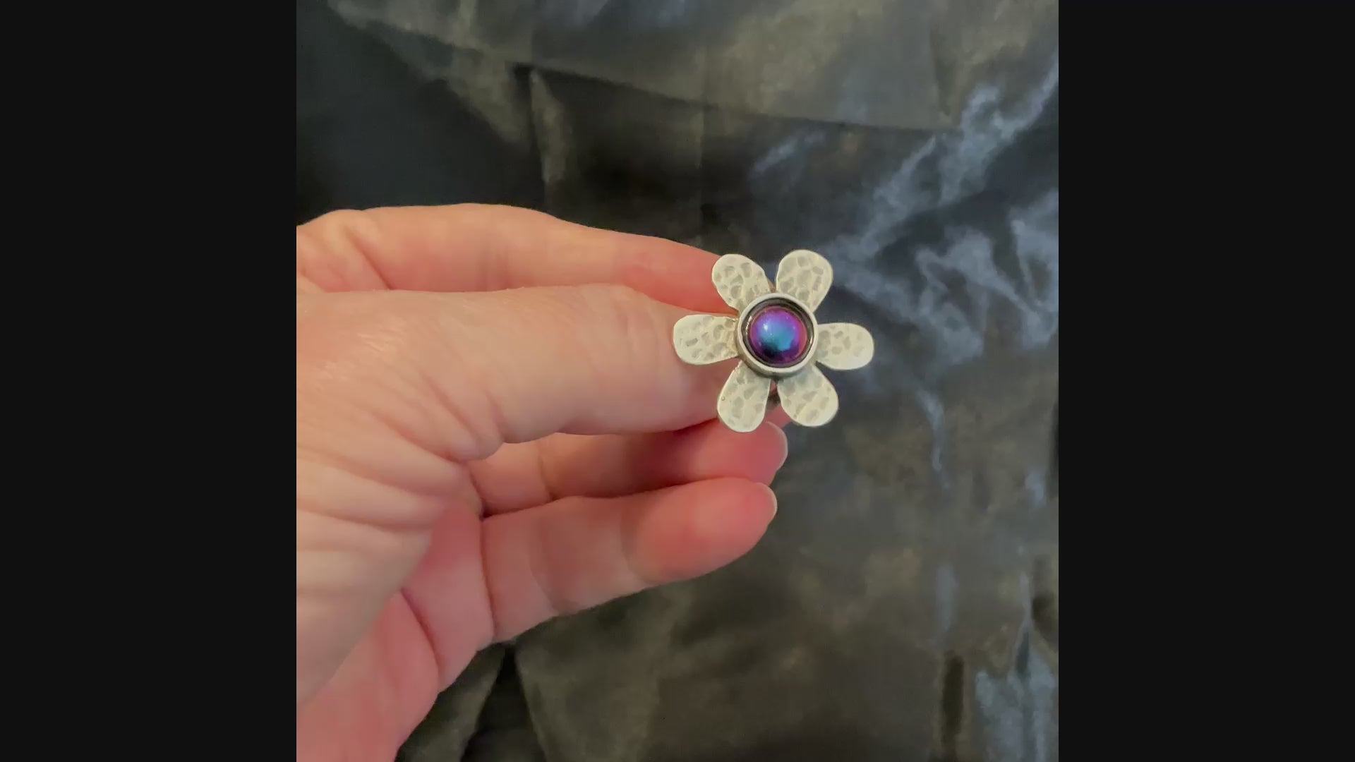 Video of the color shift flower ring showing how the resin cab shifts through shades of pink, blue, purple, yellow and green depending on how the light is hitting it.