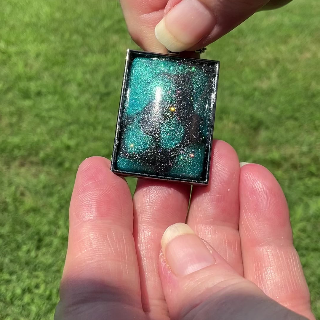Large Handmade Teal and Dark Gray Resin Gunmetal Rectangle Pendant Necklace with Glitter video showing the glitter sparkling in the light as it moves around.