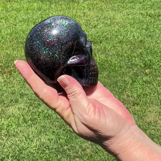 Large Black and Dark Purple Handmade Resin Skull with Holographic Glitter video showing how the glitter sparkles in the sunlight outside.