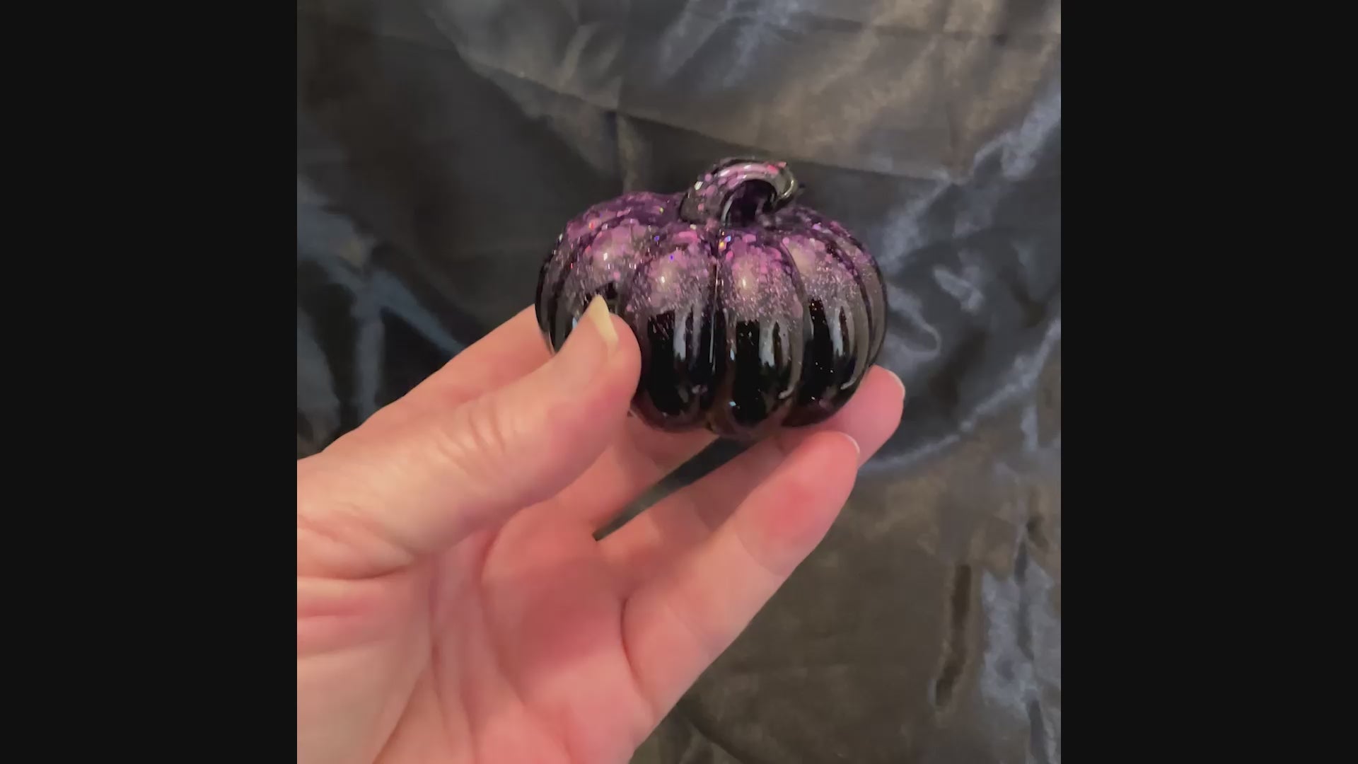 Video of the small shiny black pumpkin with purple glitter showing how the iridescent glitter sparkles in the light.