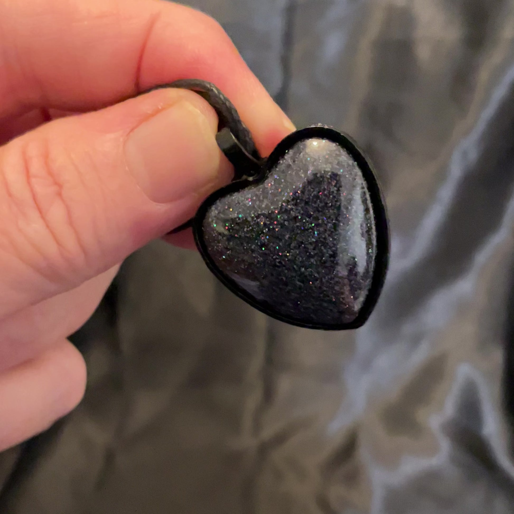 Video of the handmade Goth heart pendant necklace showing how the holographic black glitter resin sparkles in the light.