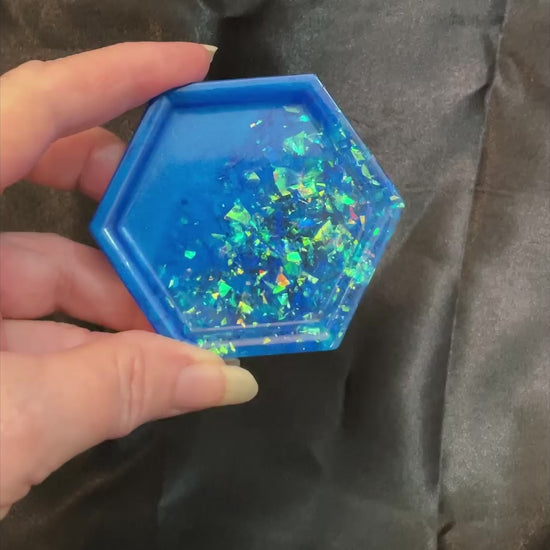 Video of the handmade ocean blue geometric hexagon small resin trinket dish showing how the iridescent glitter flakes sparkle in the light.