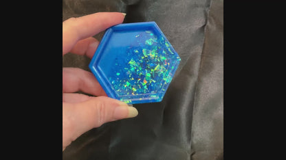 Video of the handmade ocean blue geometric hexagon small resin trinket dish showing how the iridescent glitter flakes sparkle in the light.