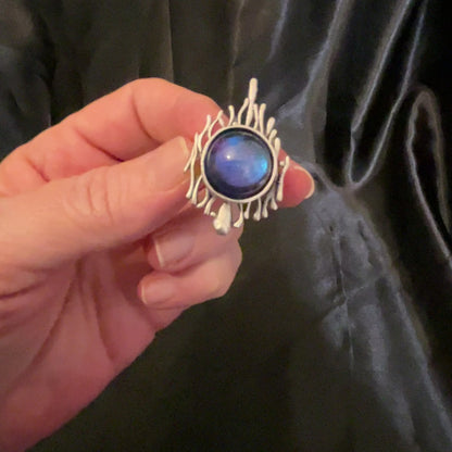 Video of the handmade Brutalist adjustable ring showing how the color shift resin cab goes from blue to purple as the light hits it.