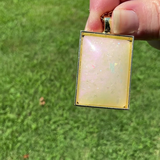 Handmade Off White and Pink Color Shift Resin Rectangle Glitter Pendant Necklace video showing the light pearly sheen and glistening of the glitter in the sunlight.