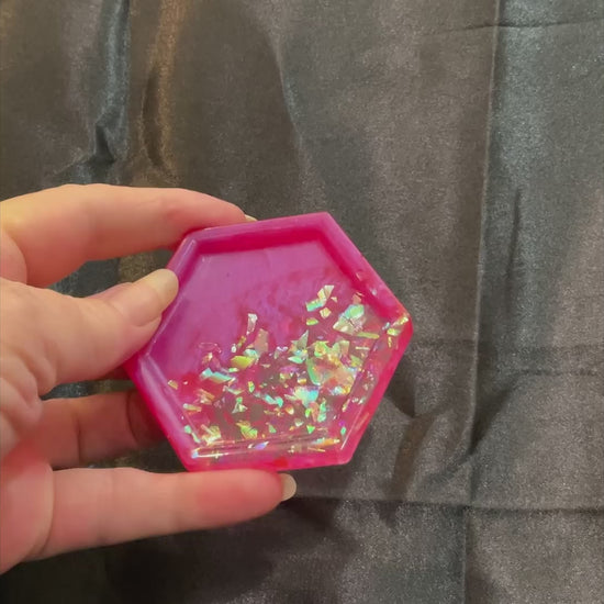 Video of the small handmade bright pink resin geometric hexagon trinket dish showing how iridescent glitter flakes sparkle in the light.