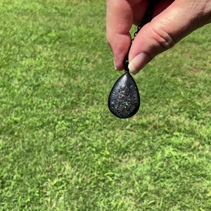 Black and Gray Handmade Resin Teardrop Pendant Necklace with Holographic Glitter video showing how it has flashes of color and sparkle as it moves around in the light.