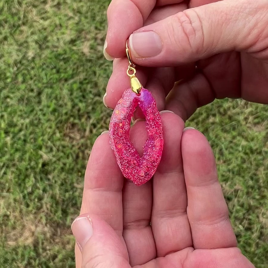 Video of the bright pink handmade resin geode style earrings showing how the glitter sparkles in the light.