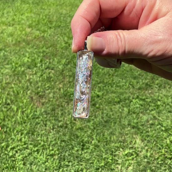 Handmade Holographic Glitter Resin Bar Pendant Necklace video showing how the glitter sparkles and flashes color as it moves around in the light.