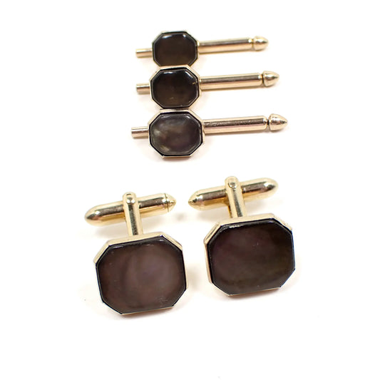 Front view of the Mid Century vintage Swank men's jewelry set. There are three shirt studs and a pair of cufflinks. Each has an octagon shape with brownish gray color abalone shell fronts. The metal is gold tone in color.