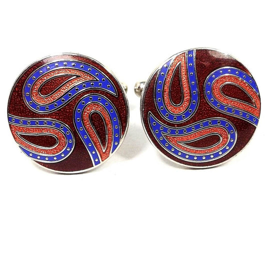 Front view of the retro vintage Joseph Abboud cufflinks. They are round with silver tone color metal. There is a paisley design with blue and red curved teardrops and a darker red enameled background.