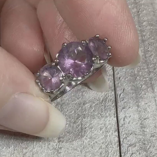 Video of the retro vintage rhinestone ring. The metal is silver tone in color. There is a large round light purple rhinestone in the middle with a smaller one on each side. The stones can take on a pink hue depending on the lighting. The video is showing how the stones sparkle.