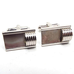 Front view of the Mid Century vintage Flex Let Quality cufflinks. They are silver tone in color. The fronts are rectangle in shape with rectangle abalone shell in a gray color. On one side of each cufflink is a corrugated domed shape, giving them a Modernist look.