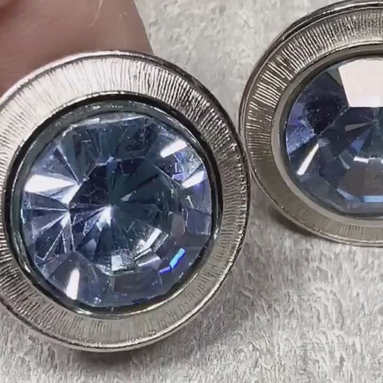Video of the Mid Century vintage rhinestone cufflinks. They are round and silver tone with large round blue rhinestones in the middle. The video is showing how they sparkle.