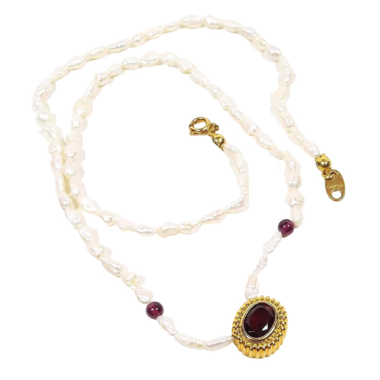 Top view of the retro vintage Avon garnet and freshwater cultured pearl beaded pendant necklace. The metal around the pendant and clasp is gold tone in color. The necklace is beaded with small rice pearls and two small round garnet beads. The bottom pendant has an oval garnet cab in the middle. 