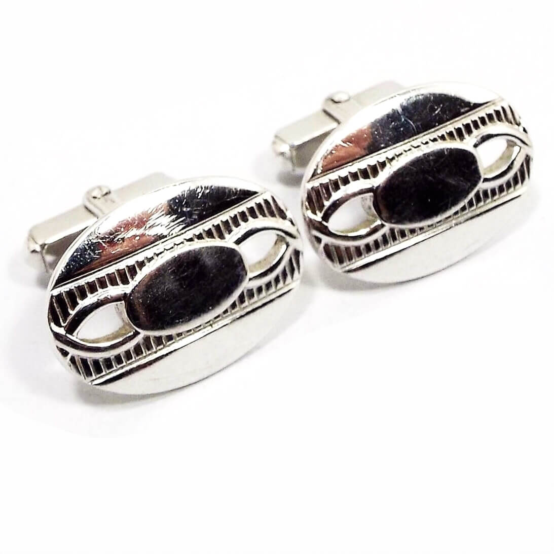Front view of the Mid Century vintage Anson cufflinks. The metal is silver tone in color. They are oval in shape with an oval in the middle and cut out shapes on each side. 