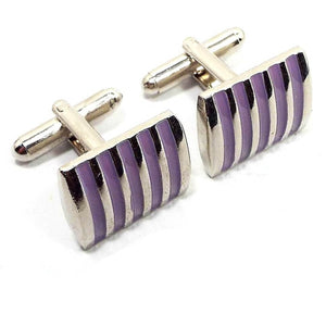Angled front view of the retro vintage enameled cufflinks. They are rectangle in shape with slightly rounded out fronts. The metal is silver tone in color and there are light purple enameled stripes. 