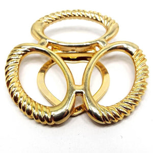 Front view of the large Mid Century vintage scarf clip. It is gold tone in color. There are three large ovals joined together in the middle. They have textured edges.