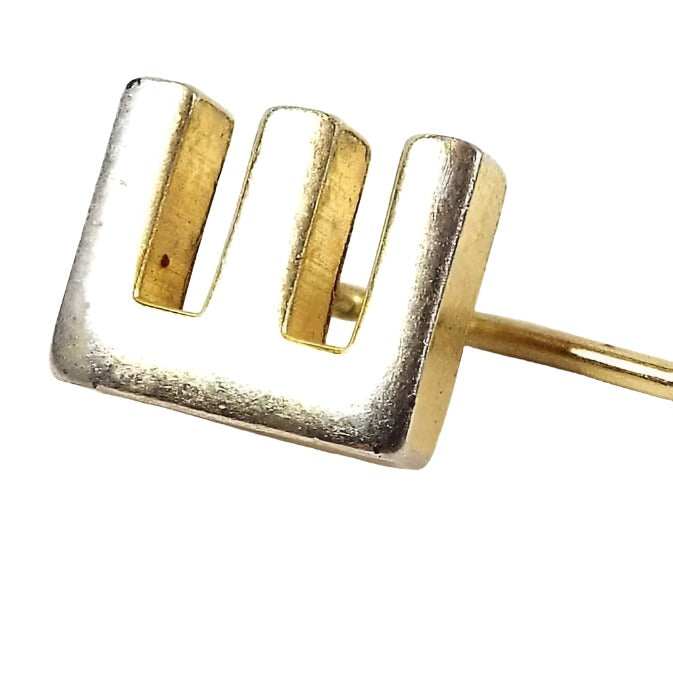 Enlarged view of the retro vintage initial stick pin. The metal is gold tone in color. There is a block letter E at the top.