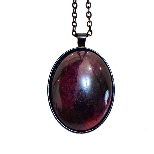 Enlarged front view of the handmade large Goth resin pendant necklace. The chain and setting are black. There is a large domed oval pendant with pearly gray and deep pink resin. There are hints of purple in the pink areas, depending on how the light hits it.