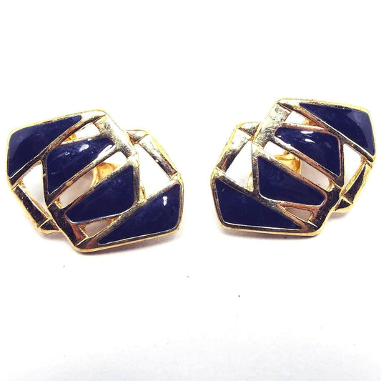 Front view of the retro vintage Monet clip on earrings. They are gold tone in color and are shaped like two faceted links together. There is dark blue enamel in the middle area.