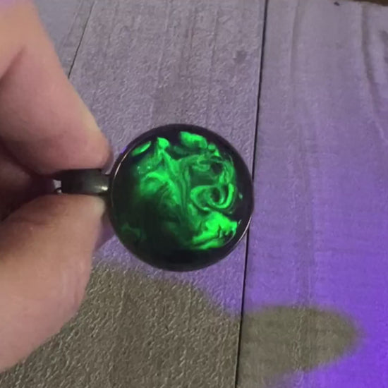 Video showing the handmade black and neon green resin necklace pendant fluorescing under a UV black light. 