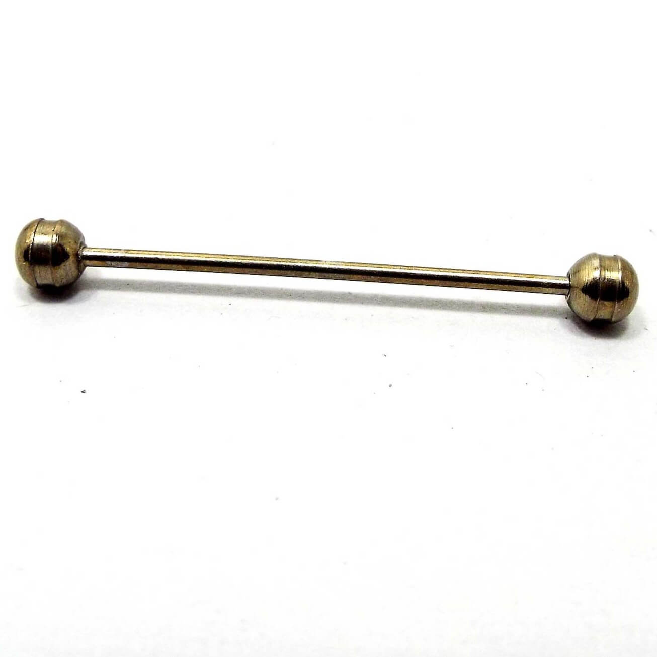 Side view of the Mid Century vintage rounded end collar bar. It is darker gold tone in color and has rounded ends with an indented cut groove on them.
