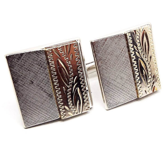 Front view of the retro vintage two tone Swank cufflinks. One side is matte silver tone color and the other is shiny very light gold tone color with etched leaf pattern.