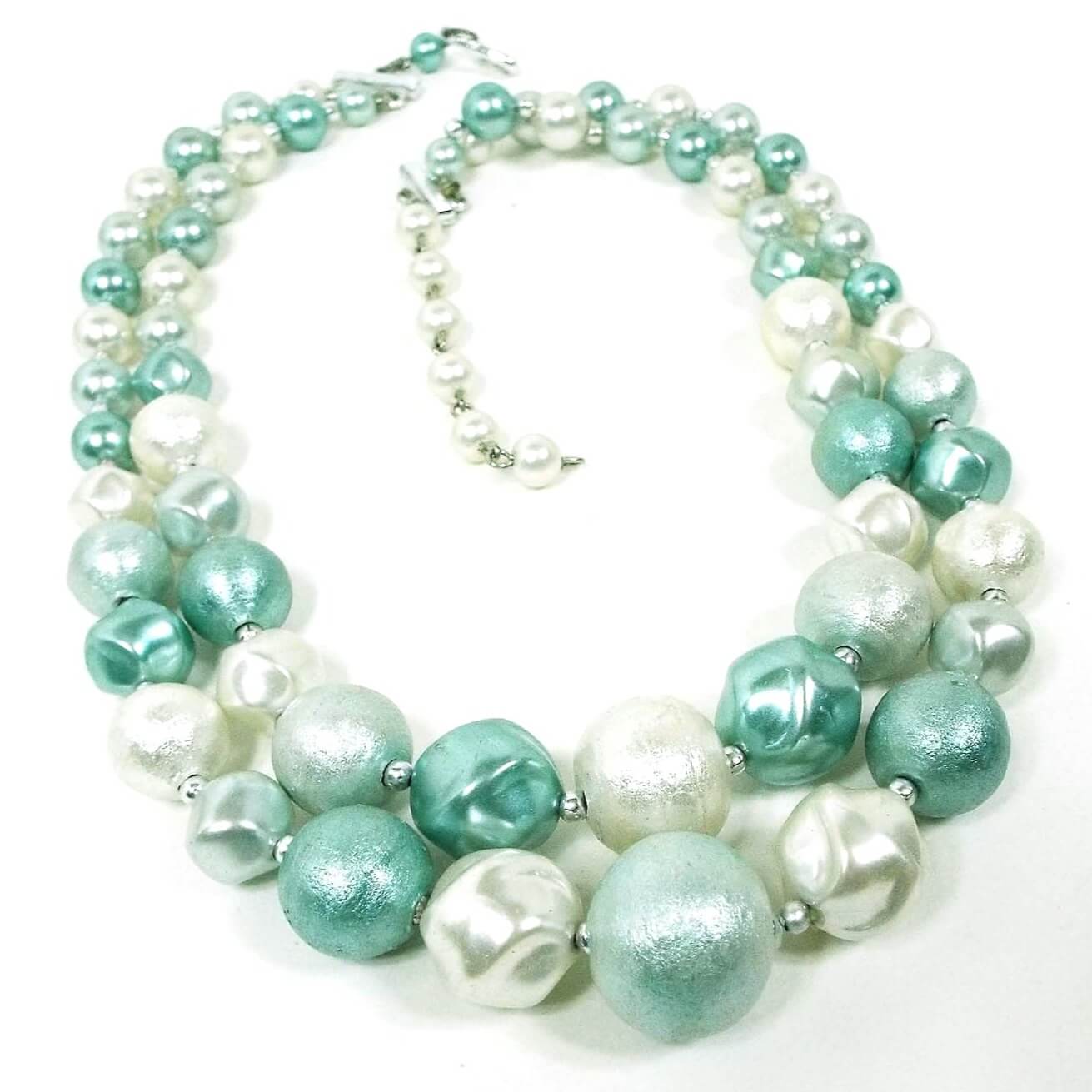 Japan Mid Century vintage multi strand beaded necklace. There are two strands of textured round and chunky styled plastic beads. The beads are mostly mint green and white in color. There is a hook clasp at the end.