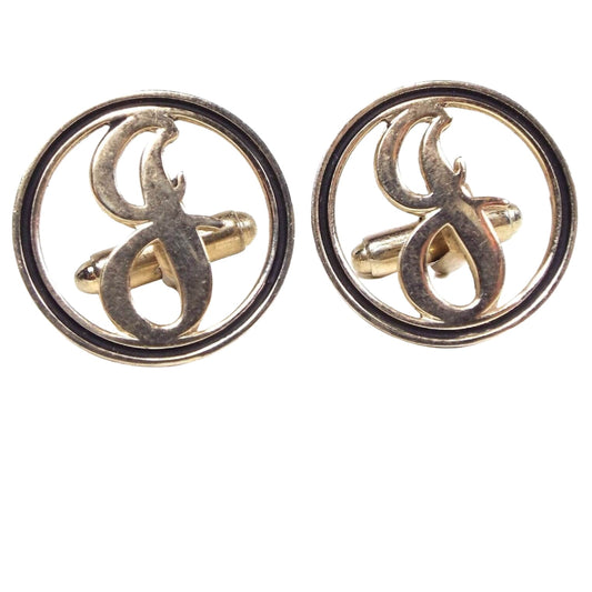 Front view of the Mid Century vintage initial cufflinks. They are round and gold tone in color with a black painted edge. There is a cut out letter J in the middle.