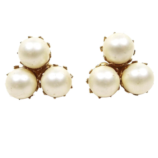 Front view of the Mid Century vintage Castlecliff clip on earrings. There are three round off white pearls in gold tone color prong settings.