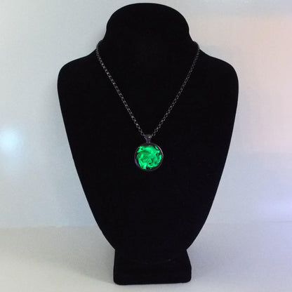 Photo showing the handmade black and neon green pendant necklace fluorescing under a UV black light.
