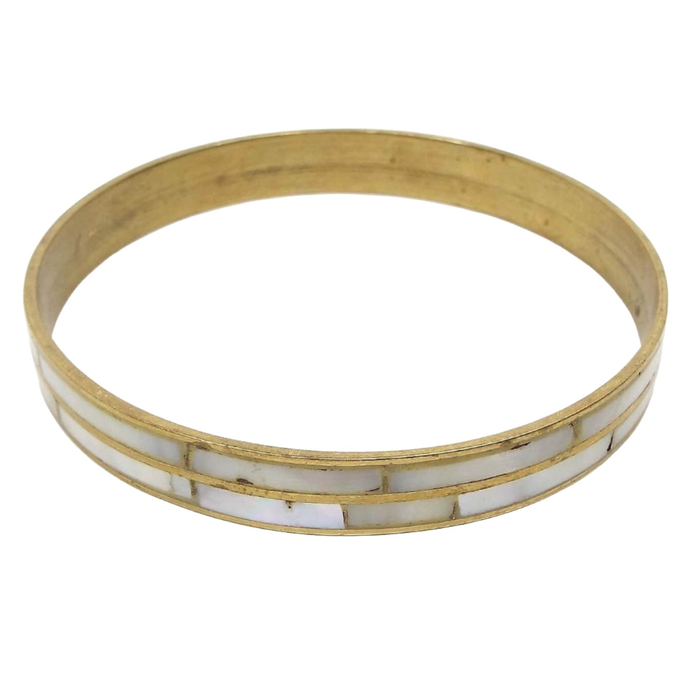 Angled view of the retro vintage brass bangle bracelet. The brass has a darkened patina for an antiqued gold kind of look. There are two rows of inlaid mother of pearl shell around the bracelet.