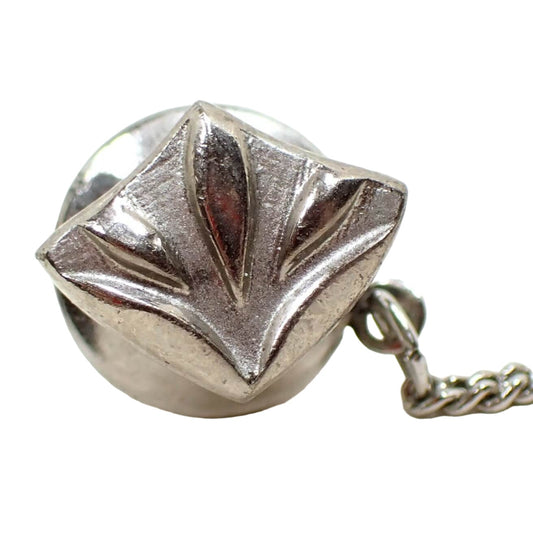 Front view of the Mid Century vintage Modernist style tie tack. It is silver tone in color. It has a point towards the bottom and the top flares out with a leaf like design.