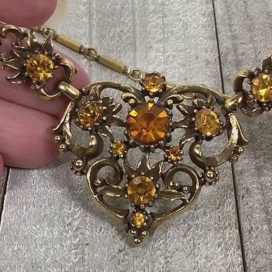 Video of the Mid Century vintage Coro rhinestone necklace. There are round citrine color orange rhinestones on the pendant bottom part of the necklace. The video is showing how they sparkle.