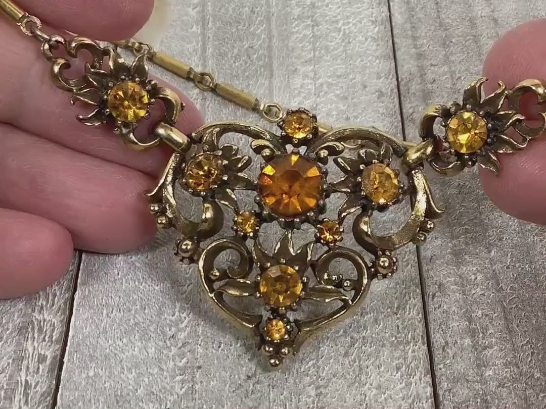 Video of the Mid Century vintage Coro rhinestone necklace. There are round citrine color orange rhinestones on the pendant bottom part of the necklace. The video is showing how they sparkle.