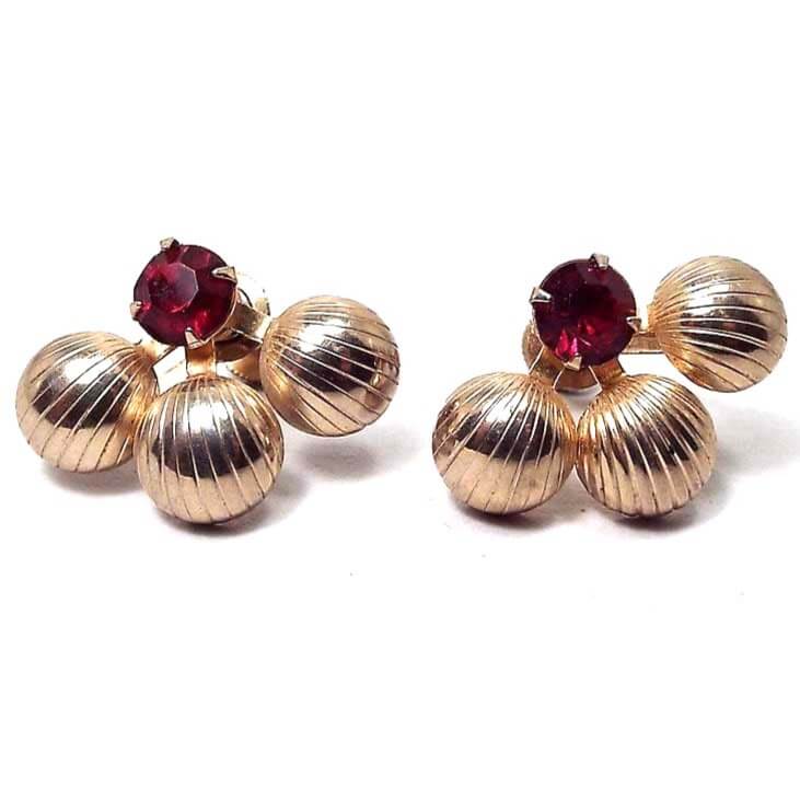 Front view of the Mid Century vintage Duane screw back earrings. They are gold tone in color. There are three round areas with lines on the bottoms that are spread out similar to a fan like design. At the top is a round prong set rhinestone in dark red.