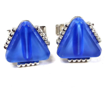 Front view of the Mid Century vintage triangle cufflinks. The metal is silver tone in color. The fronts have blue glass rounded triangles. there is a line of silver tone dots on each side of the triangle. 