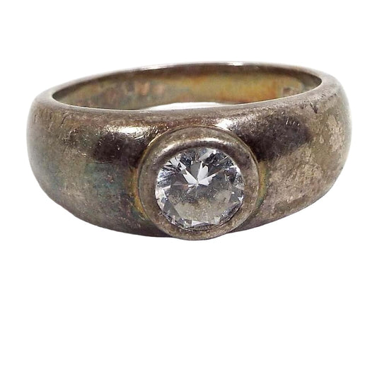 Front view of the retro vintage sterling silver band ring with cubic zirconia solitaire. The silver is darkened in color to a gray from age. The top has a rounded bezel with a round cut CZ stone in the middle. 