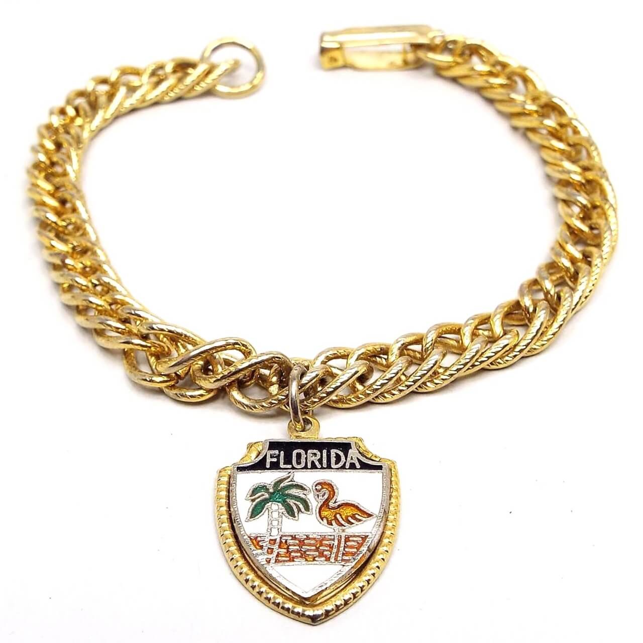 Front view of the retro vintage charm bracelet. The chain is gold tone in color and has a curb link chain. The charm at the bottom is shaped like a shield and has Florida at the top with a palm tree and a flamingo on it. 