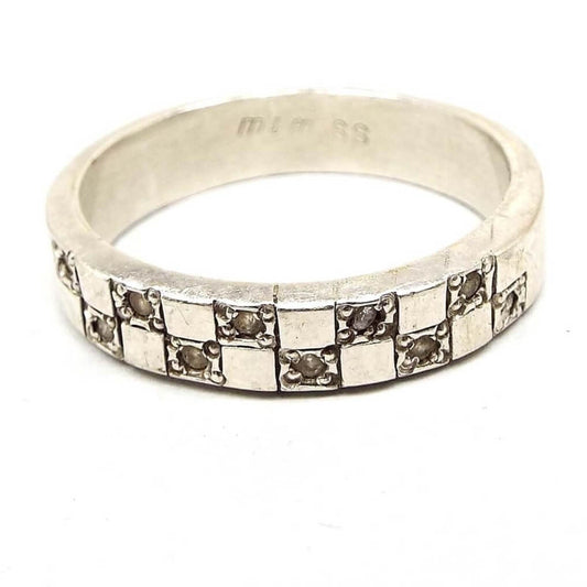 Front view of the retro vintage sterling silver cubic zirconia band ring. The top of the ring has a checkboard like design with squares. Every other square has a small round prong set CZ stone set in it. There are ten CZ stones total.