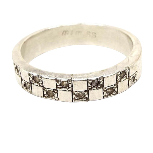 Front view of the retro vintage sterling silver cubic zirconia band ring. The top of the ring has a checkboard like design with squares. Every other square has a small round prong set CZ stone set in it. There are ten CZ stones total.
