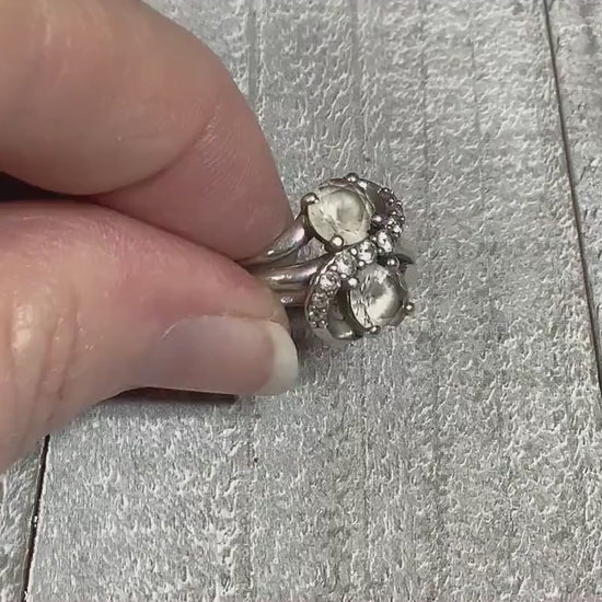 Video of the retro vintage Sai Krishna sterling silver ring with white sapphires. The top has an S like pattern with small round clear white sapphires on it. On either side of the curves are larger white sapphire stones. The video is showing how the stones sparkle.