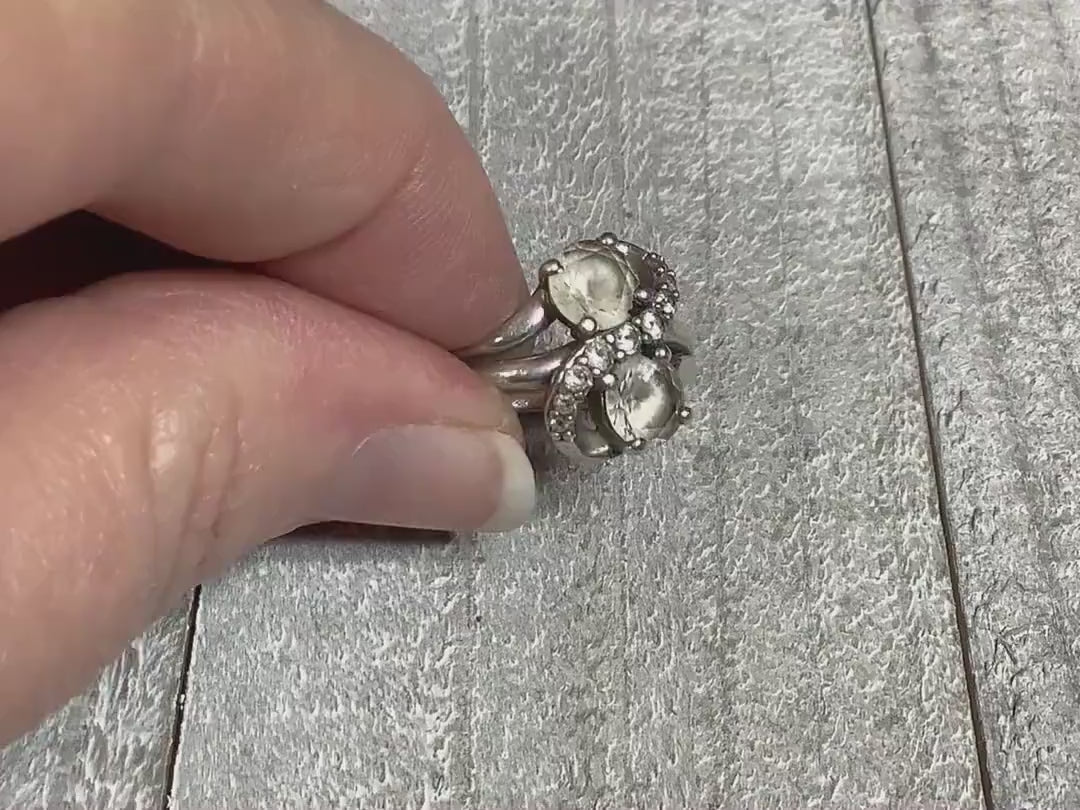 Video of the retro vintage Sai Krishna sterling silver ring with white sapphires. The top has an S like pattern with small round clear white sapphires on it. On either side of the curves are larger white sapphire stones. The video is showing how the stones sparkle.